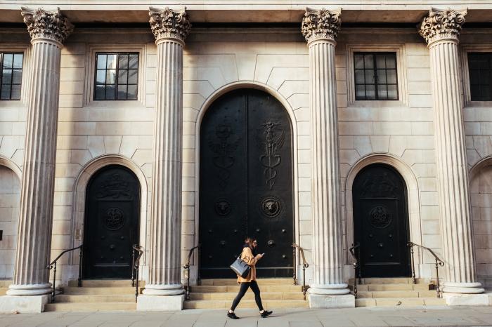 woman walking in front of bank entrance 