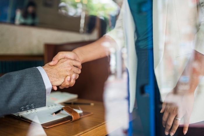 two business people shaking hands in office financial advisor transitions 